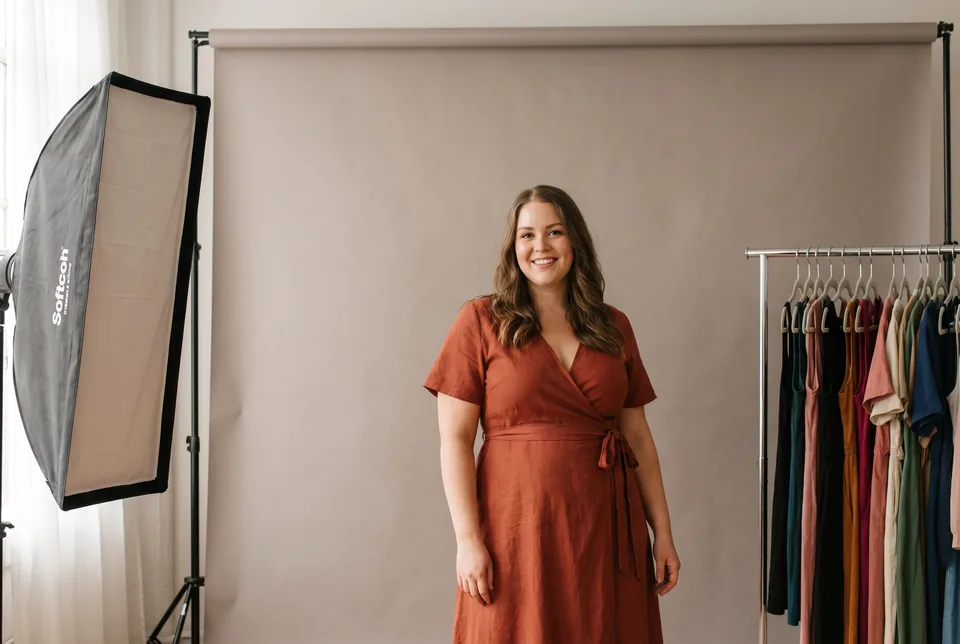 Model standing in front of a studio backdrop beside a softbox, lit from the side